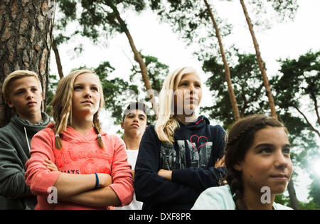 Portrait of group of children standing next to trees in park with arms crossed, looking forward in same direction, Germany Stock Photo
