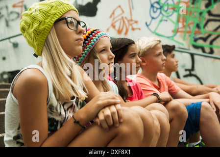 Group of children sitting on stairs outdoors, looking forward in the same direction, Germany Stock Photo