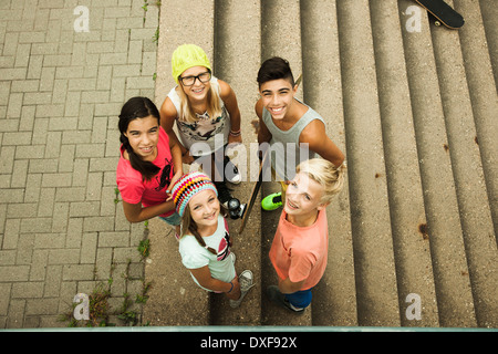 Group of children standing outdoors on cement staris, looking up at camera, Germany Stock Photo
