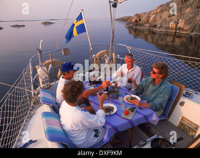 Two couples having picnic on board sailing vessel at Storra Nassa Island group in Stockhom Archipelago Stock Photo