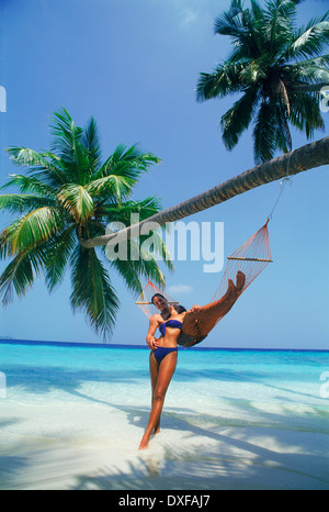 Couple on island holidays relaxing in hammock on sandy beach in paradise Stock Photo