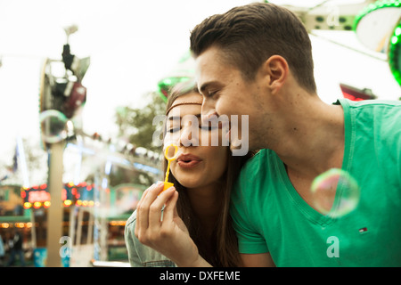 Close-up portrait of young couple blowing bubbles at amusement park, Germany Stock Photo