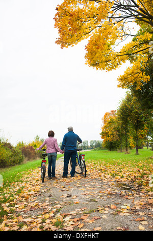 Couple Walking Bicycles on Path in Autumn, Mannheim, Baden-Wurttmeberg, Germany Stock Photo