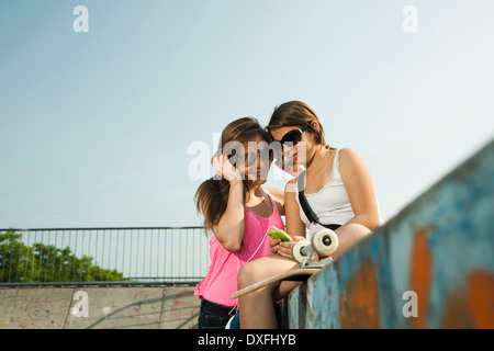 Girls Looking at MP3 Player in Skatepark, Feudenheim, Mannheim, Baden-Wurttemberg, Germany Stock Photo