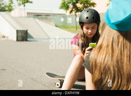 Girls using Cell Phone in Skatepark, Feudenheim, Mannheim, Baden-Wurttemberg, Germany Stock Photo