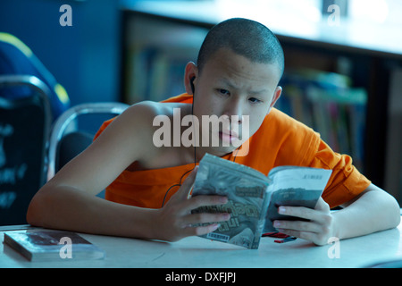 Young Monk reading a book while listening to music Stock Photo