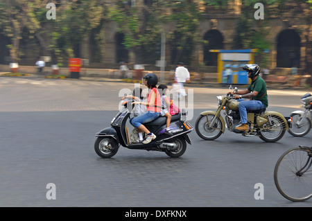 A mother rides on a motor scooter with her two young children through the busy traffic on the center of Mumbai. Stock Photo