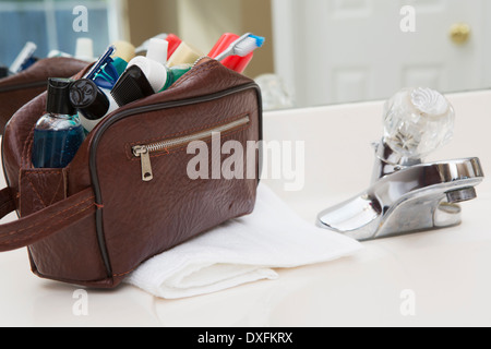 Men's toiletry travel bag on bathroom counter, filled with toothbrush, lotion, razor and other grooming products, USA Stock Photo