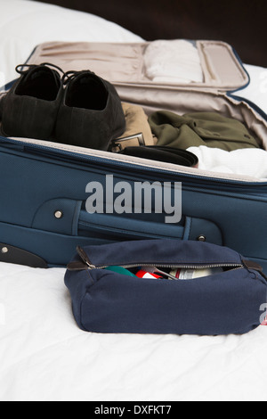 Men's toiletry travel bag beside packed suitcase on bed, USA Stock Photo