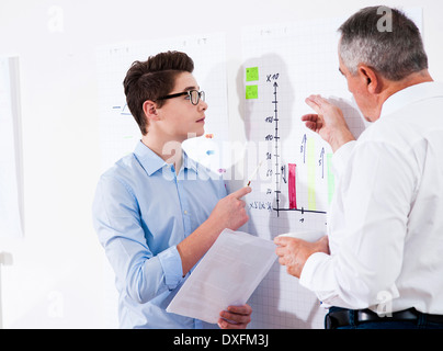 Businessman explaining chart to apprentice in office, Germany Stock Photo