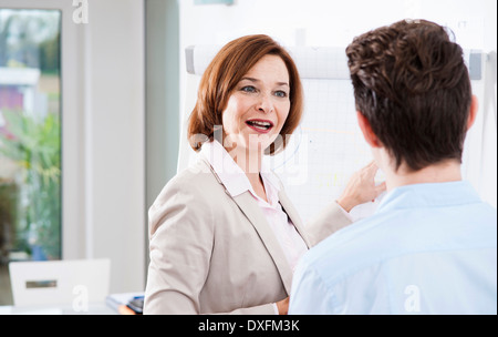 Businesswoman explaining work to apprentice in office, Germany Stock Photo