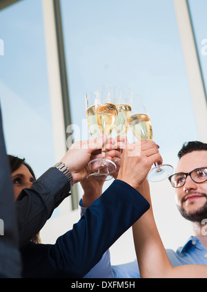 Business people holding champagne glasses and toasting each other in office, Germany Stock Photo