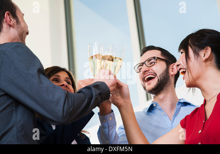 Business people holding champagne glasses and toasting each other in office, Germany Stock Photo