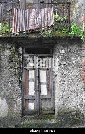 Old door and balcony of an abandoned dwelling in Southern Italian village of Delianuova Calabria Stock Photo