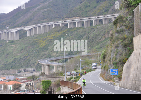 Cyclist on a cycling holiday of Calabria and Sicily, along Calabrian coastline and Autostrada A3 in background. Stock Photo