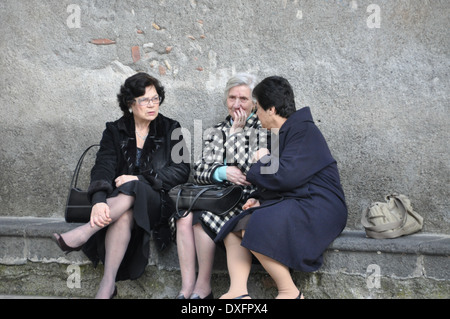 Three elderly women sitting on a bench chatting and passing the time of day Stock Photo