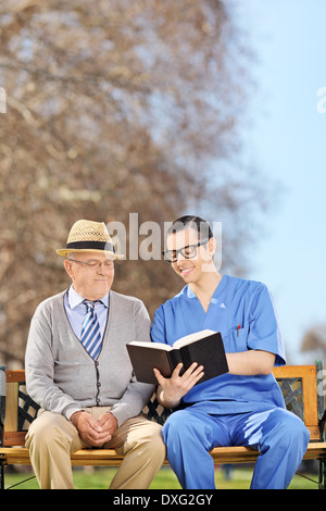 Male nurse reading to a pensioner in park Stock Photo