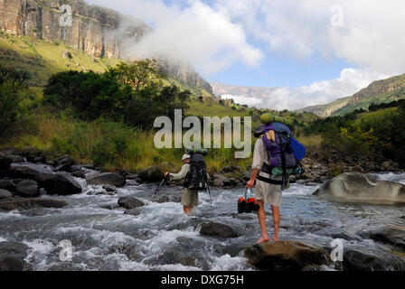 Hikers crossing a full Njesuthi River, Drakensberg mountains Stock