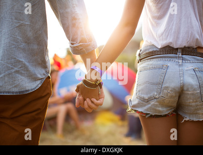 Couple holding hands near tents at music festival Stock Photo