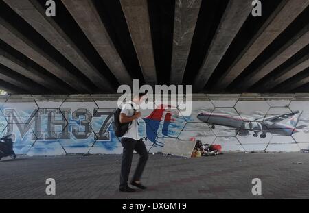 Kuala Lumpur, Malaysia. 26th Mar, 2014. A man walk past a graffiti featuring missin Malaysia Airlines flight MH370 displayed on a wall in Kuala Lumpur on March 26, 2014. New 122 debris spotted are not far from earlier objects sighted by the French and Chinese satellites said Acting Transport Minister Datuk Seri Hishammuddin Tun Hussein.Photo: Firdaus Latif/NurPhoto © Firdaus Latif/NurPhoto/ZUMAPRESS.com/Alamy Live News Stock Photo