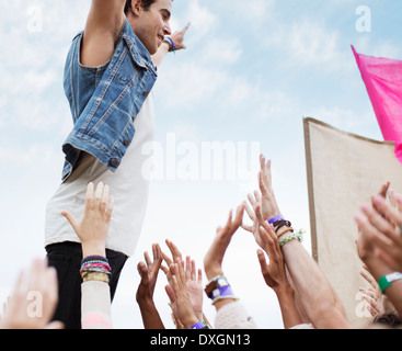 Performer standing above cheering crowd at music festival Stock Photo