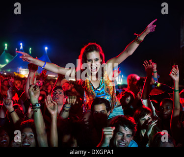 Cheering woman on manÍs shoulders at music festival Stock Photo