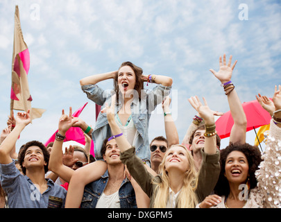 Cheering woman on manÍs shoulders at music festival Stock Photo