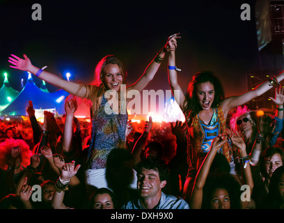 Cheering women on menÍs shoulders at music festival Stock Photo