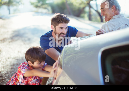 Multi-generation men pushing car at roadside Stock Photo