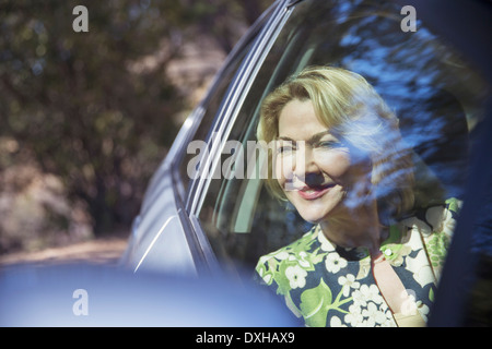 Happy senior woman looking at car window Stock Photo