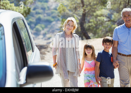 Grandparents and grandchildren holding hands outside car Stock Photo