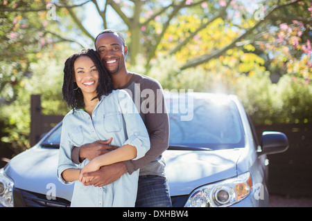 Portrait of happy couple hugging outside car Stock Photo