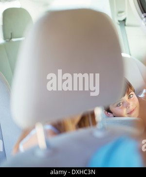 Mother turning to talk to children in back seat of car Stock Photo