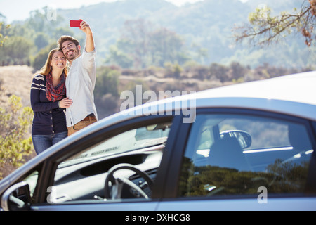 Couple taking self-portrait with cell phone outside car Stock Photo