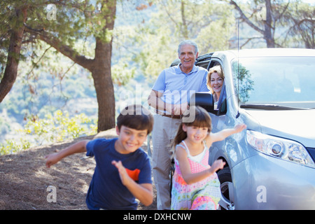 Grandparents watching grandchildren running outside car Stock Photo