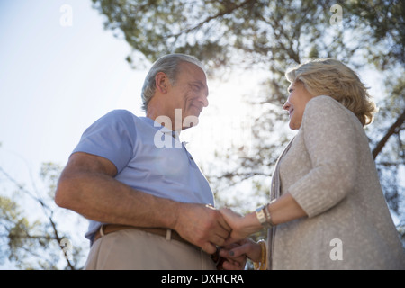 Happy senior couple holding hands under tree Stock Photo