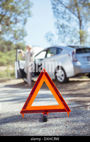 Woman talking on cell phone with automobile hood raised at roadside Stock Photo