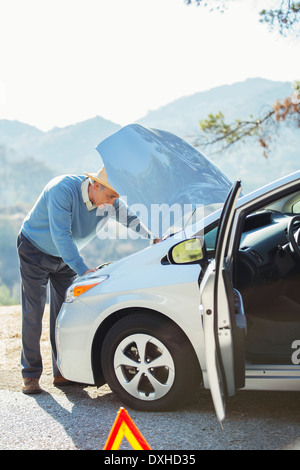 Man looking at car engine at roadside Stock Photo