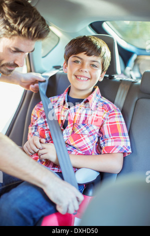 Father fastening seat belt for boy in back seat of car Stock Photo