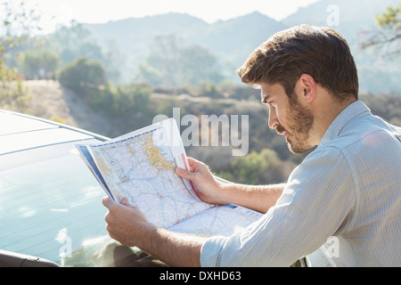 Man looking at map outside car Stock Photo