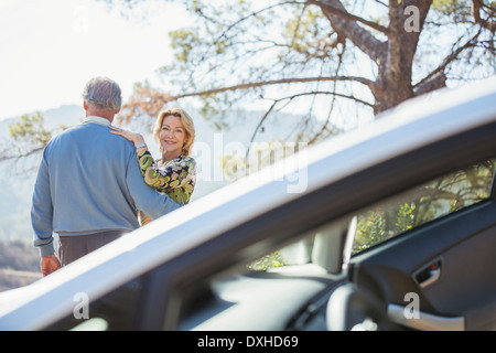 Senior couple hugging at roadside outside car Stock Photo