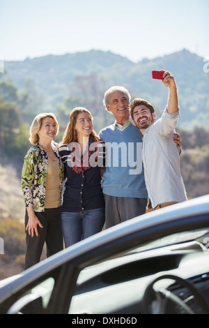 Family taking self-portrait with cell phone outside car Stock Photo