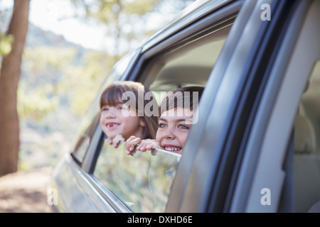 Happy brother and sister looking out car window Stock Photo