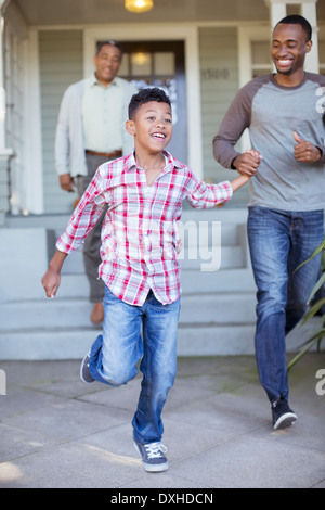 Father and son holding hands and running outside house Stock Photo