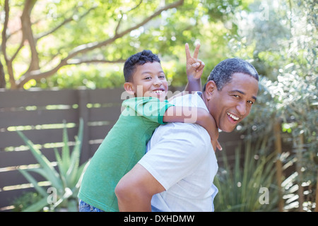 Portrait of happy grandfather piggybacking grandson Stock Photo