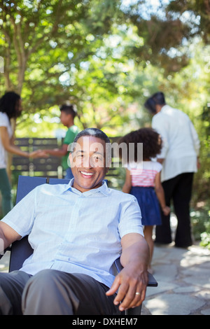 Portrait of smiling senior man on patio with family in background Stock Photo