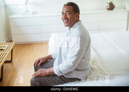 Portrait of smiling senior man sitting at the edge of bed Stock Photo