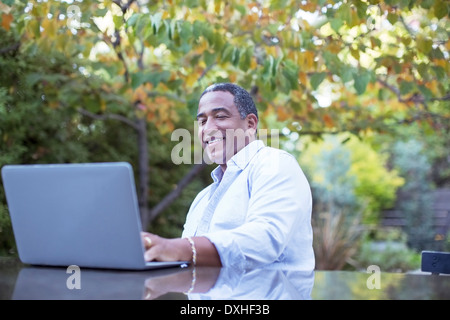 Senior man using laptop at patio table Stock Photo