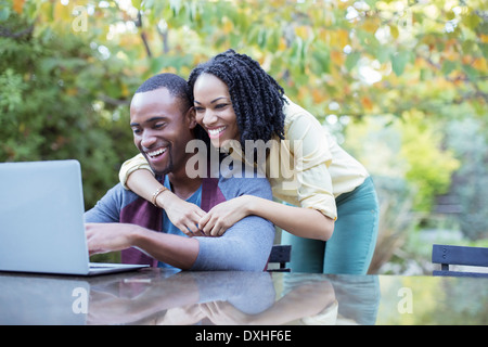 Happy couple using laptop at patio table Stock Photo