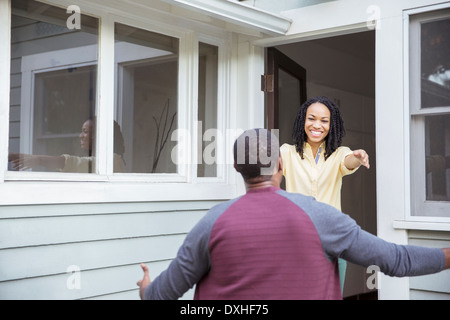 Enthusiastic woman greeting man in doorway Stock Photo